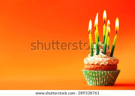 Birthday cupcake with candles on color background