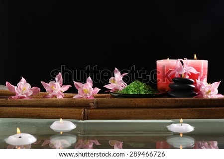 Beautiful spa composition with flowers and candles on black background