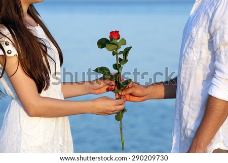 Young man giving flower for his girlfriend on beach