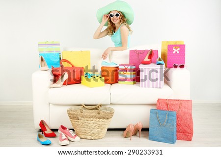 Woman with shopping bags and shoes on sofa in room