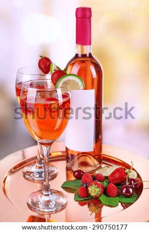 Glasses of wine with strawberries and lime on metal tray on blurred background