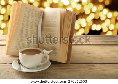Cup of coffee with open book on bright background
