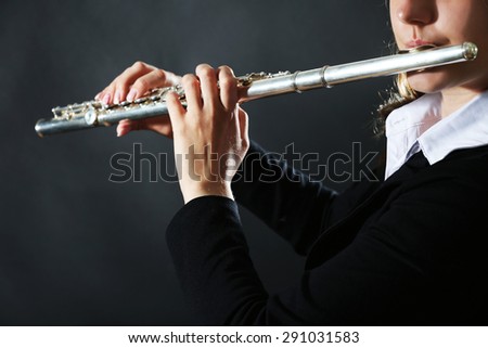 Musician playing flute on dark background