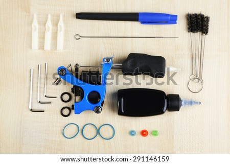 Tattoo machine and tattoo Supplies, on wooden background