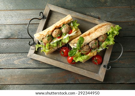 Homemade Spicy Meatball Sub Sandwich on tray, on wooden table background