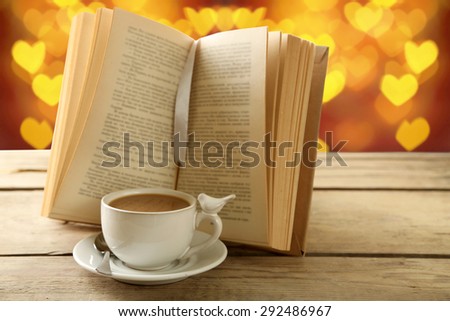 Cup of coffee with open book on bright background