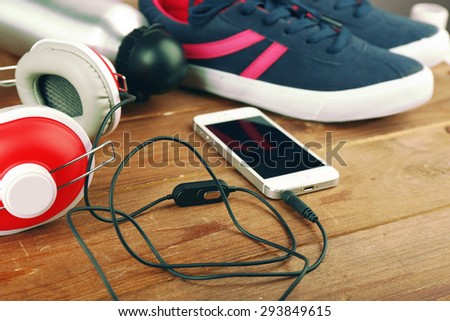 Sport shoes with bottle of water and headphones on wooden background