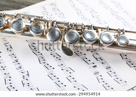 Silver flute on music notes background