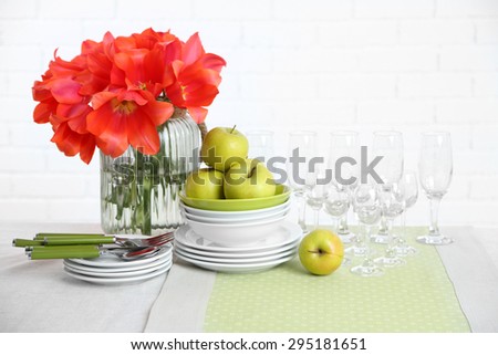Table settings and tulip flowers in vase on table, on light background