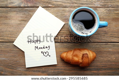 Cup of coffee with fresh croissant and Happy Monday massage on wooden table, top view