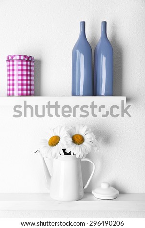 Decorative vases on wooden shelf  on white wallpaper background