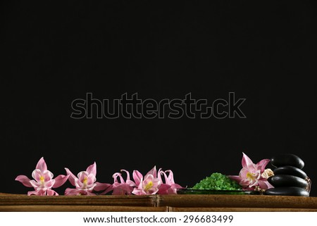 Beautiful spa composition with flowers and stones on black background