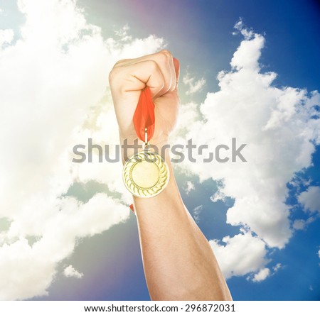 Golden medal in hand on sky background