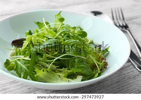 Fresh mixed green salad in bowl close up