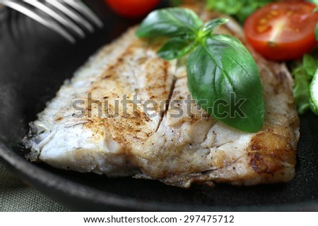 Dish of fish fillet with salad on dripping pan close up
