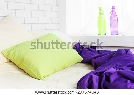 Comfortable bed with green pillow and purple blanket  in bedroom