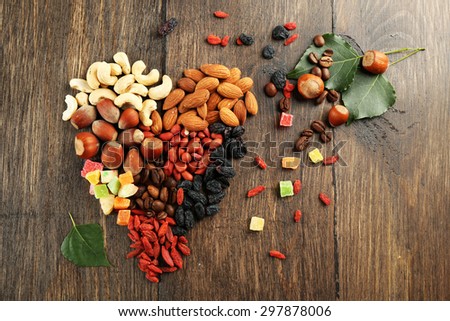 Nuts and dried fruits arranged in heart shape on wooden background