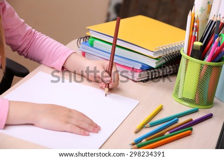 Kids hands drawing on notebook at desktop, closeup