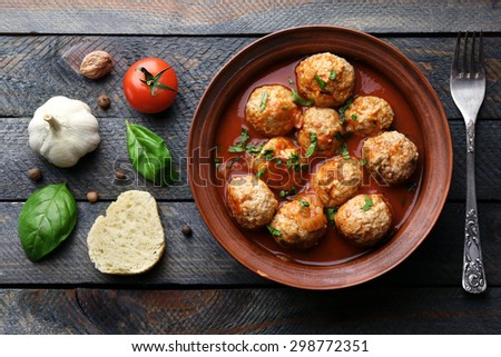 Meat balls with tomato sauce and ingredients on wooden background