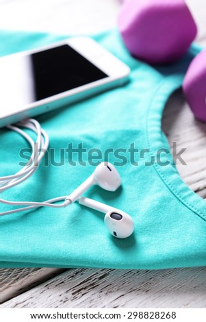 Mobile phone and earphones with set for sports on wooden table, closeup