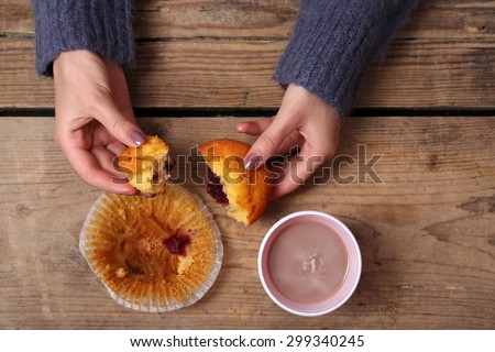 Female hands holding cup of coffee and cookies on wooden table close up