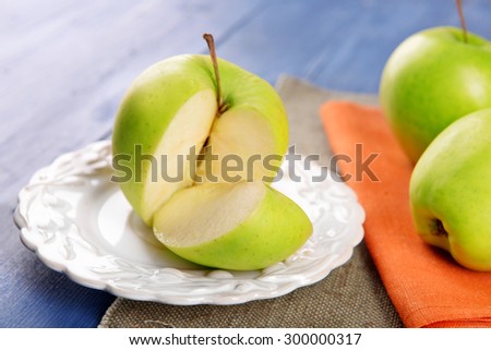 Sliced green apple in saucer on wooden table with napkins on wooden table, closeup