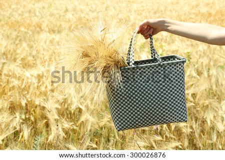 Female hand holding bag with sheaf outdoors