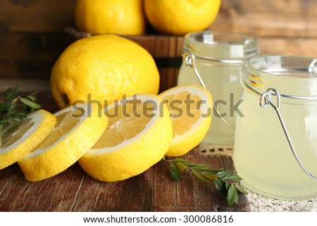 Still life with lemon juice and sliced lemons on wooden table, closeup
