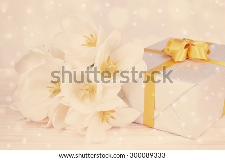 Beautiful bouquet of white tulips and gift box on table on light background