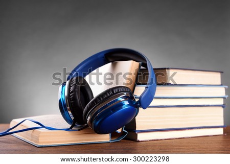 Books and headphones as audio books concept on grey background