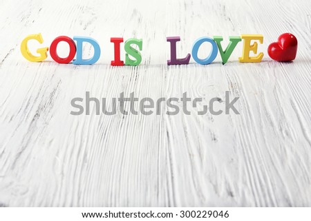 GOD IS LOVE sign illustrated with colorful plastic letters on white wooden background