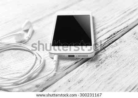 Mobile phone and earphones on wooden background