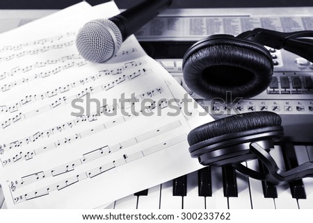 Headphones with music notes and microphone on synthesizer close up