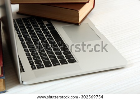 Laptop with book on table close up