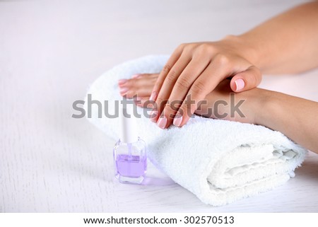 Woman hands with french manicure on towel on wooden table close-up