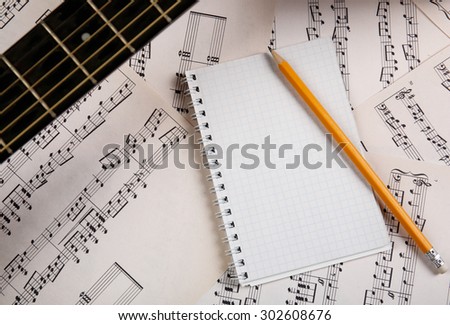 Music recording scene with guitar and memo pad on music sheets background
