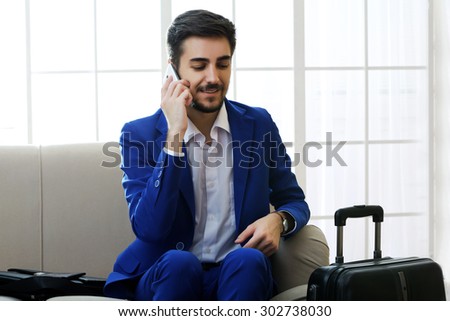 Business man with suitcase sitting on sofa in hall