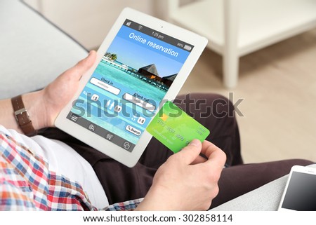 Man holding tablet with screen interface of booking hotels