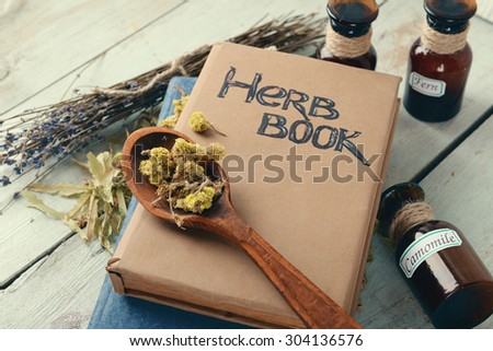 Different dried herbs and books on table close up