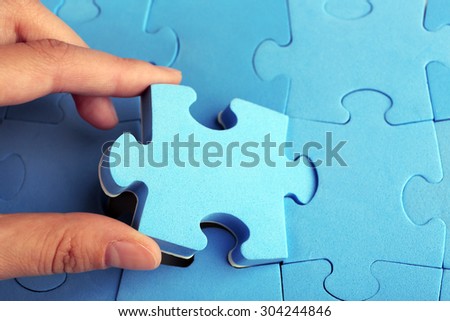 Female hand placing last piece of puzzle, closeup