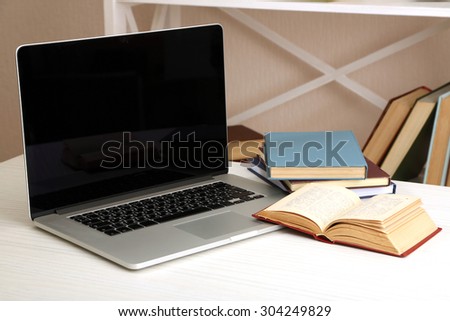 Laptop with books on table in room
