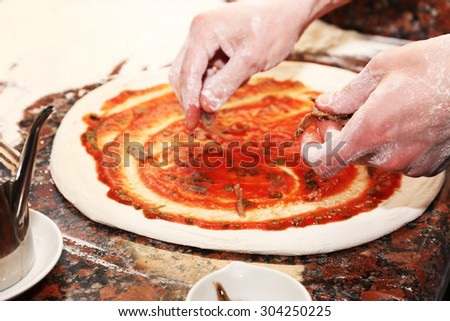 Chef preparing pizza on marble table, closeup