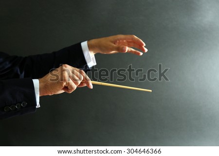 Music conductor hands with baton on black background