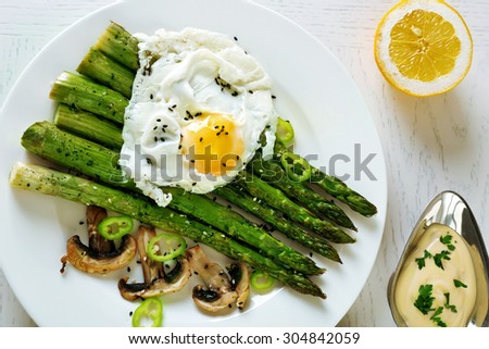 Roasted asparagus with poached egg on plate on table background