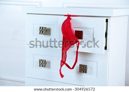 White wooden chest of drawer with bra in opened drawer