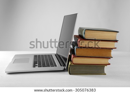 Stack of books with laptop on gray background
