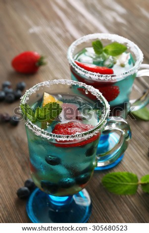 Glasses of berries juice on wooden table, closeup