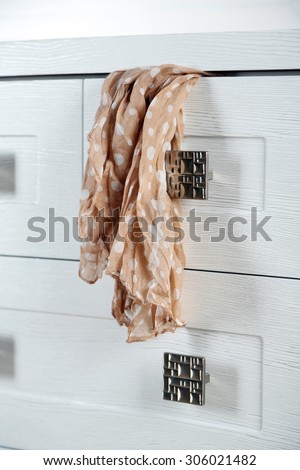 White wooden chest of drawer with scarf in opened drawer
