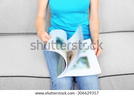 Woman reading magazine on sofa, close up