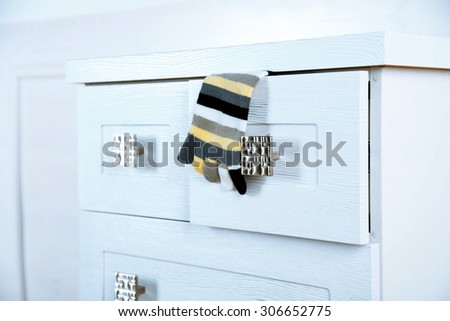 White wooden chest of drawer with sock in opened drawer